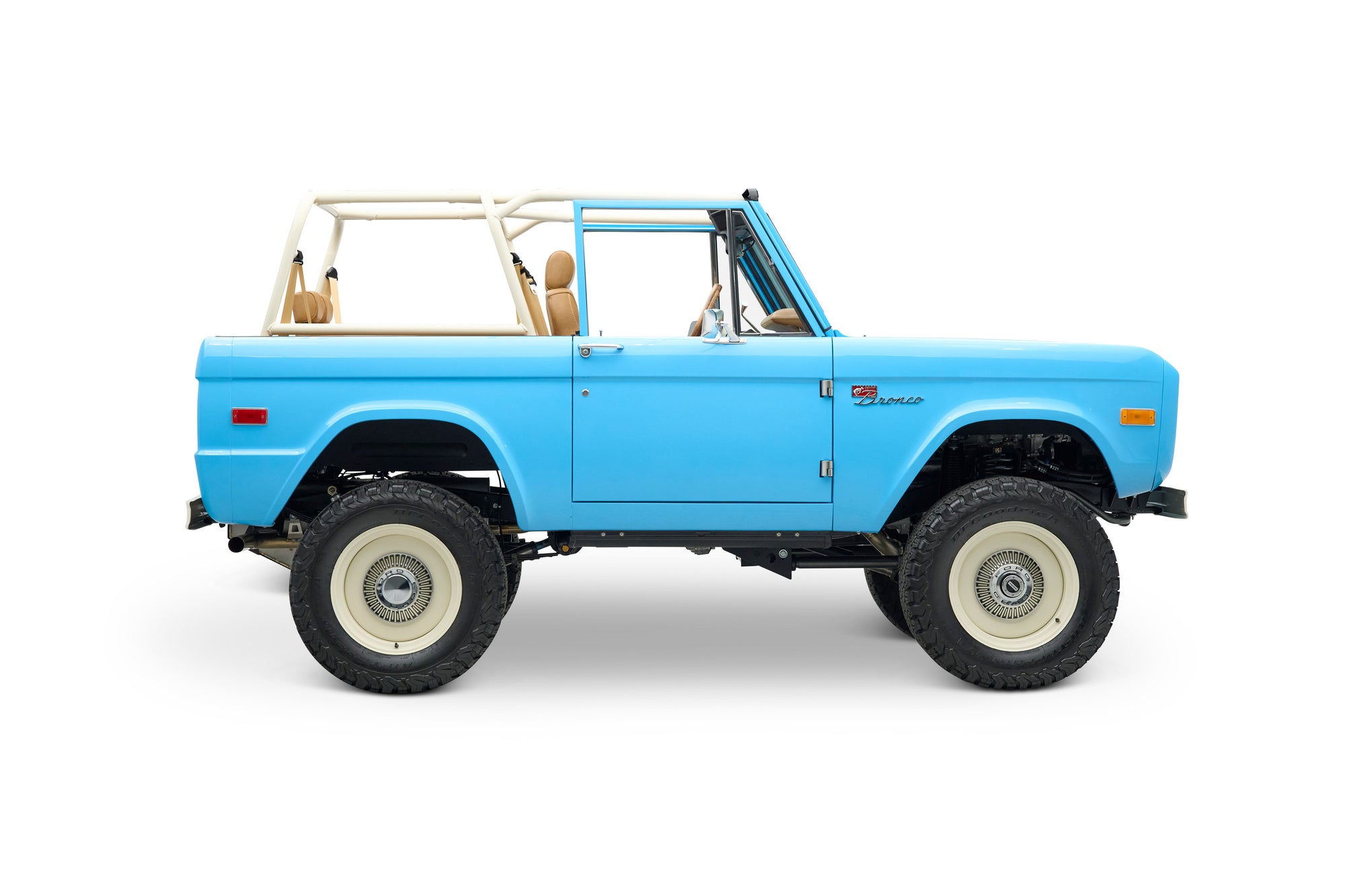 Side view of light blue Classic Ford Bronco with beige roll cage and seats