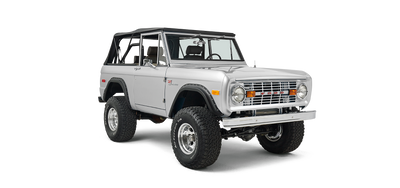 Silver Classic Ford Bronco with black soft top shown in front three-quarter view