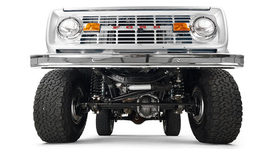 Silver Classic Ford Bronco front suspension and undercarriage view with tires and grille.