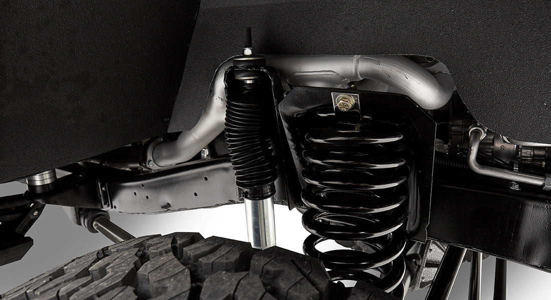 Close-up of suspension coil spring and shock absorber above tire in Classic Ford Bronco