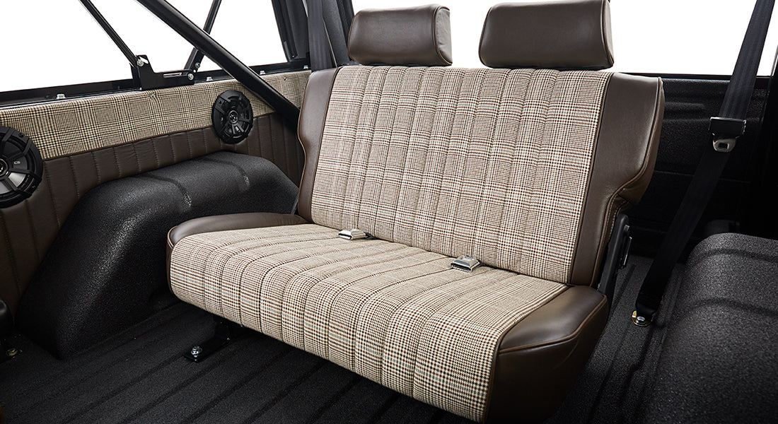 Rear bench seat with brown leather and plaid upholstery inside Classic Ford Bronco