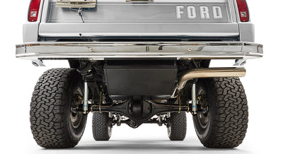 Rear view of silver Classic Ford Bronco showing suspension, exhaust, and FORD tailgate lettering.