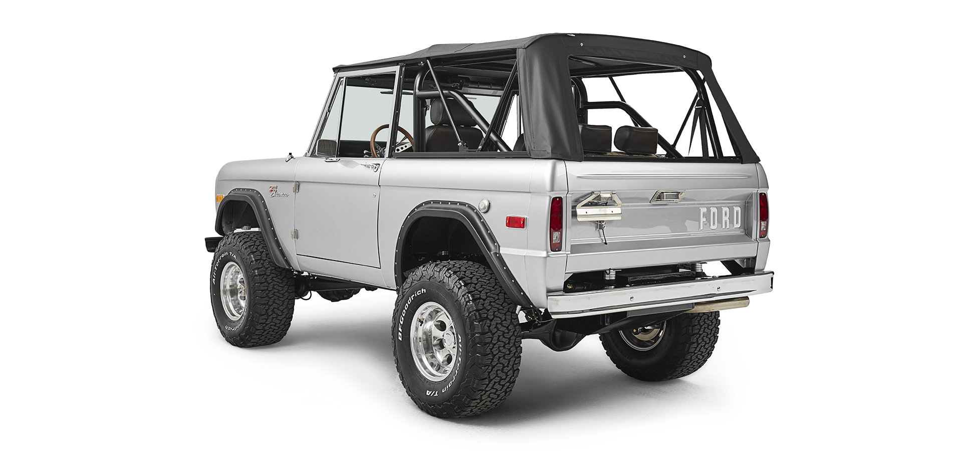 Silver Classic Ford Bronco with black soft top shown from rear three-quarter angle