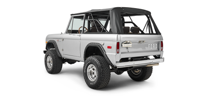 Silver Classic Ford Bronco with black soft top shown from rear three-quarter angle