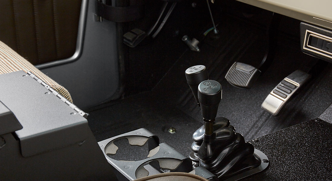 Classic Ford Bronco driver footwell with gear selector levers and pedals.