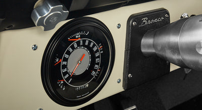 Close-up of Classic Ford Bronco dashboard showing speedometer and Bronco emblem plate.