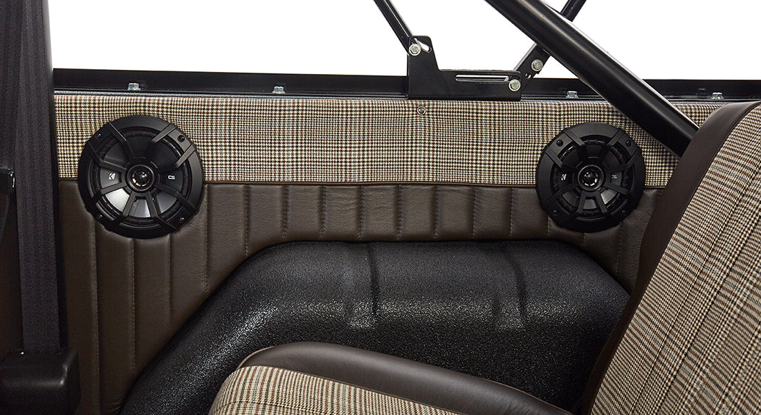 Interior side panel of Classic Ford Bronco showing tan and brown upholstery and speakers.