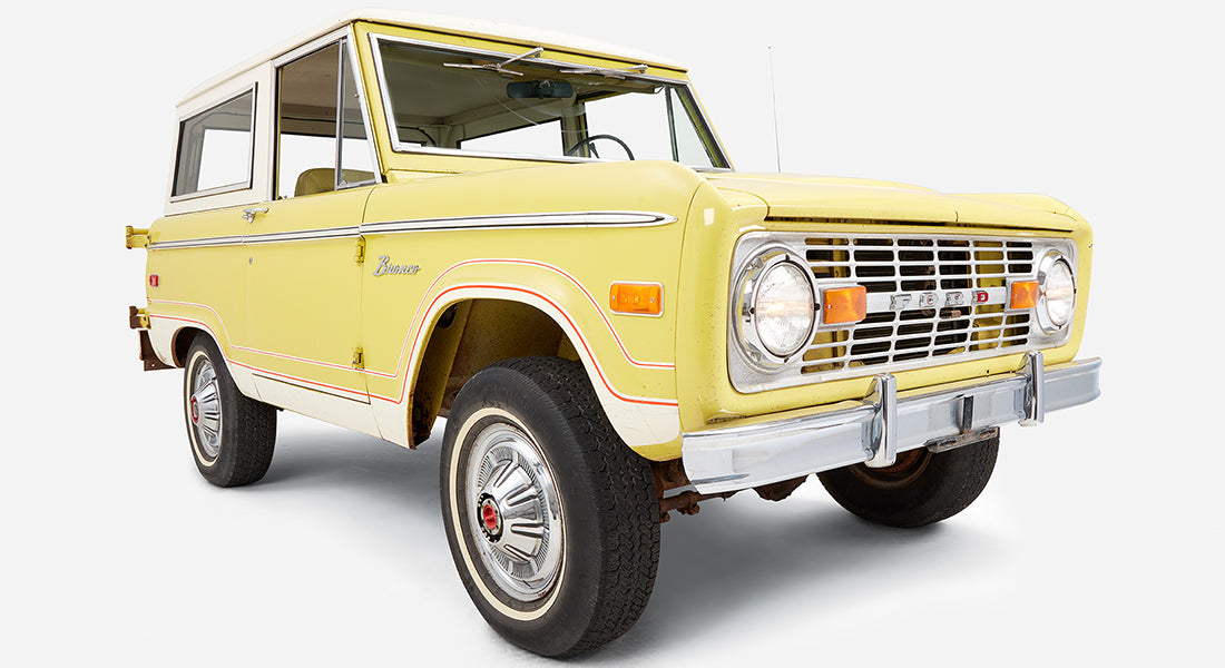 Yellow Classic Ford Bronco angled front view showing driver door and tires