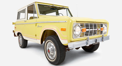 Yellow Classic Ford Bronco angled front view showing driver door and tires