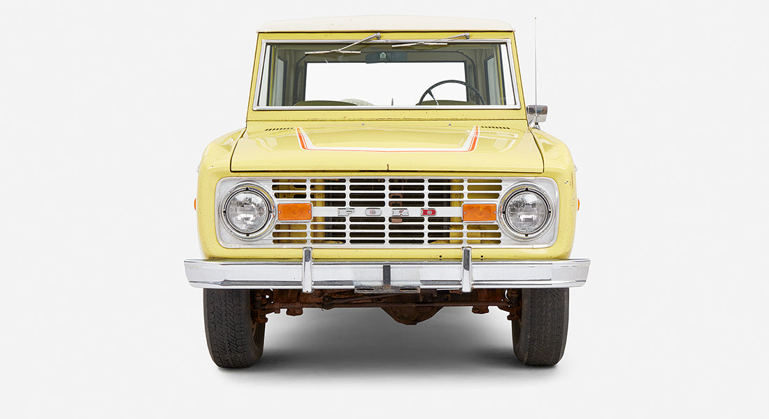 Front view of yellow Classic Ford Bronco with chrome bumper and headlights