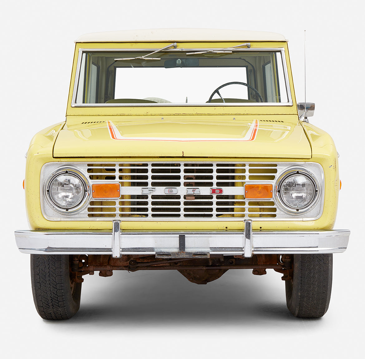 Close-up front view of yellow Classic Ford Bronco with visible grille and headlights