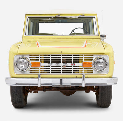 Close-up front view of yellow Classic Ford Bronco with visible grille and headlights