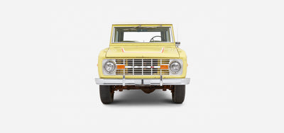 Yellow Classic Ford Bronco front view with white roof and red stripe detailing