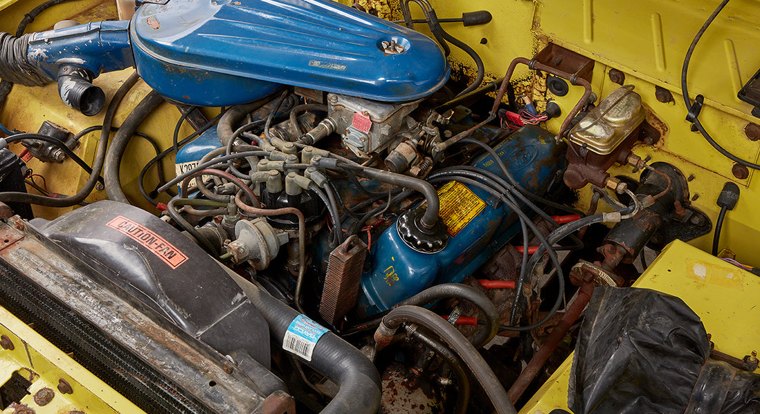 Close-up of engine components inside Classic Ford Bronco under open hood with blue air cleaner