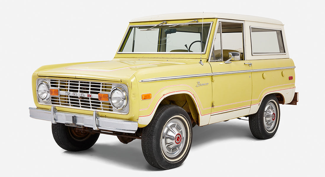 Yellow and white Classic Ford Bronco displayed at an angle showing front and side panels