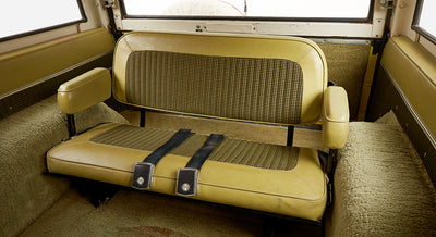 Rear interior bench seat of Classic Ford Bronco with yellow and black houndstooth upholstery and seat belts