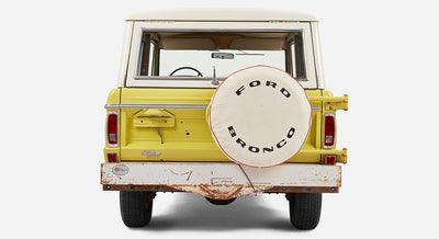 Rear view of yellow Classic Ford Bronco with white spare tire cover