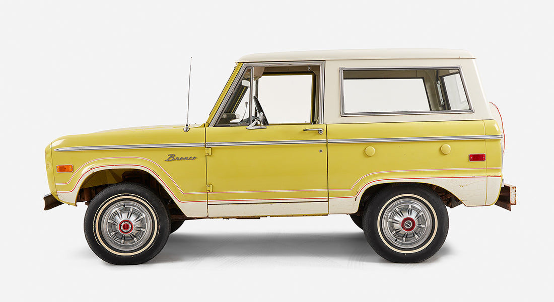 Opposite side profile of yellow Classic Ford Bronco with white roof and red pinstriping