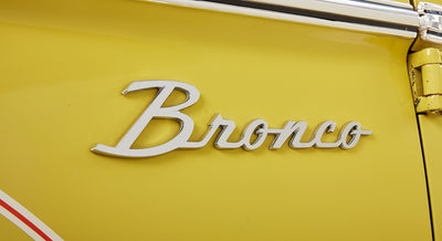 Close-up of silver Classic Ford Bronco emblem on yellow door