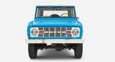 Blue Classic Ford Bronco front view with white roof and visible suspension underneath