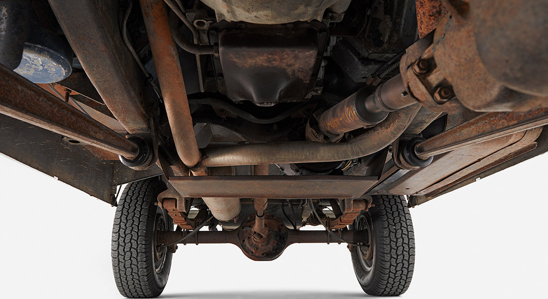Underside of a vehicle showing chassis, exhaust, and suspension components with two tires