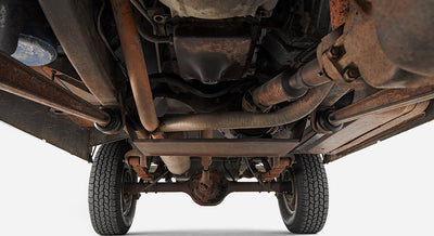 Underside of a vehicle showing chassis, exhaust, and suspension components with two tires
