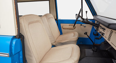 Classic Ford Bronco interior showing side view of beige front seats with blue and white door
