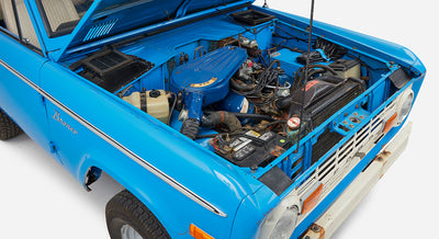 Classic Ford Bronco with open hood displaying engine bay and blue body with white roof