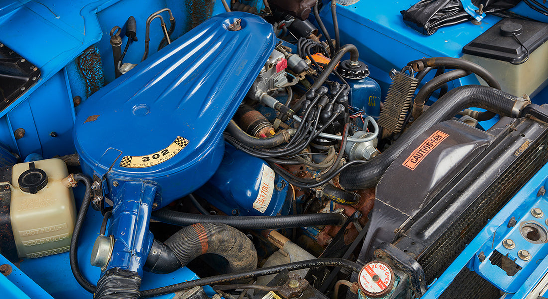 Close-up of Classic Ford Bronco engine bay showing blue engine cover labeled '302 Cubic Inches