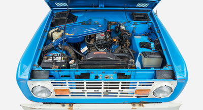 Classic Ford Bronco engine bay viewed from the front with radiator, battery, and engine components