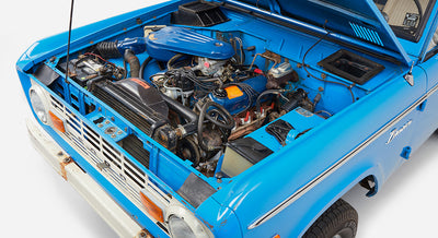 Side angle of Classic Ford Bronco engine bay showing blue engine and surrounding components