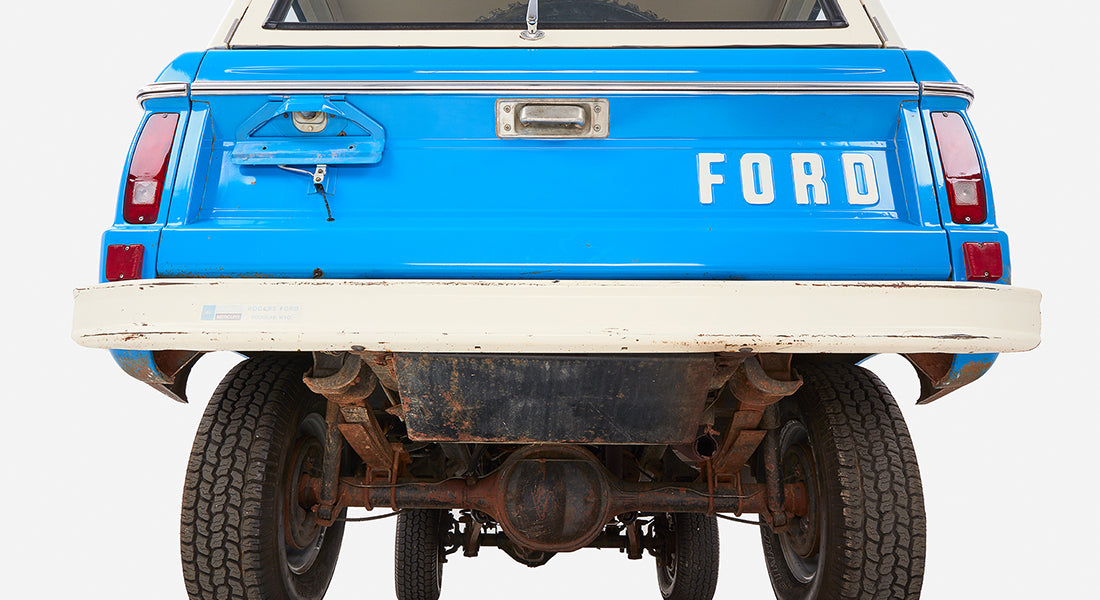 Rear view of a Classic Ford Bronco showing blue tailgate with 'FORD' letters and white bumper