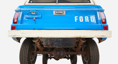 Rear view of a Classic Ford Bronco showing blue tailgate with 'FORD' letters and white bumper