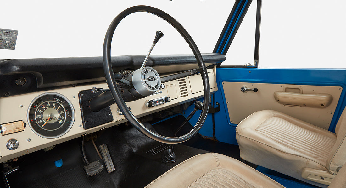 Close-up of Classic Ford Bronco dashboard with steering wheel and beige seat