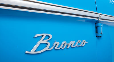 Blue Classic Ford Bronco side panel with chrome Bronco emblem and door hinges