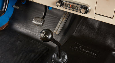 Gear shift and pedals on black floor mat with Bronco logo in Classic Ford Bronco