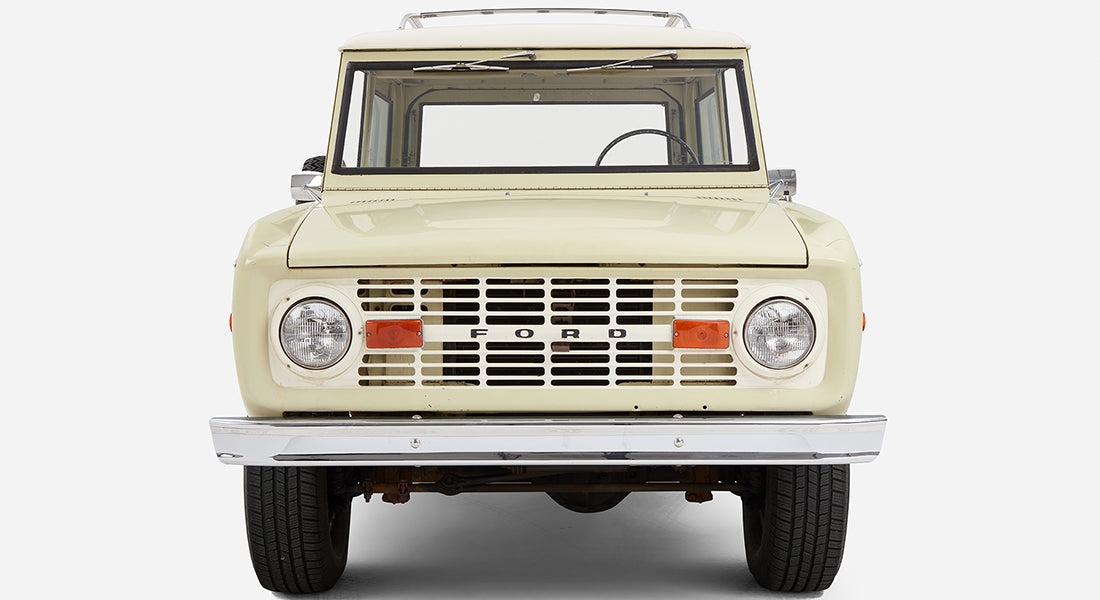 Light sage green Classic Ford Bronco with white roof, front view showing grille and headlights