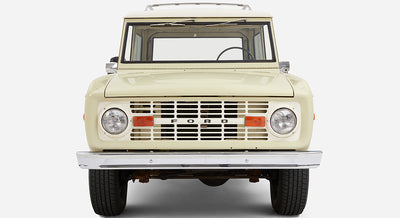 Light sage green Classic Ford Bronco with white roof, front view showing grille and headlights
