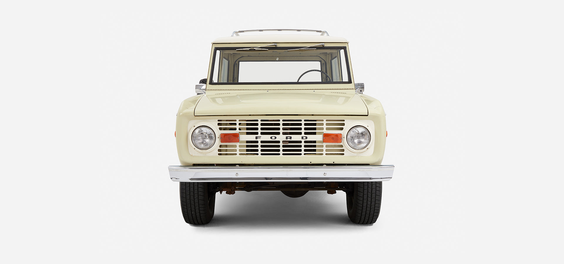 Front view of Classic Ford Bronco displaying grille, headlights, and bumper on white background
