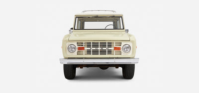 Front view of Classic Ford Bronco displaying grille, headlights, and bumper on white background