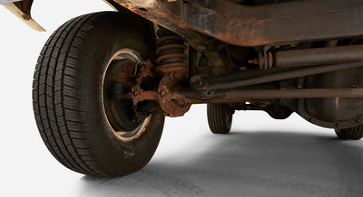 Rusty suspension and wheel axle visible underneath a vehicle on a white background