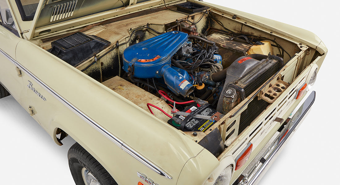 Front interior view of Classic Ford Bronco showing bench seat, steering wheel, dashboard, and gear shift