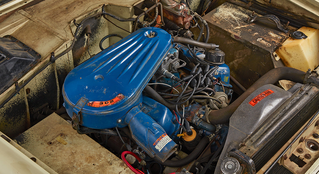 Engine bay of Classic Ford Bronco with visible blue engine block and various engine components