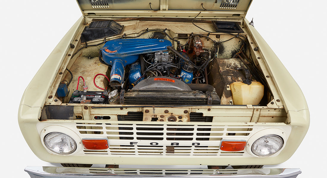 Classic Ford Bronco front grille with open hood showing blue air filter and engine components