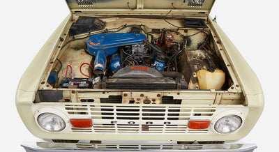 Classic Ford Bronco front grille with open hood showing blue air filter and engine components