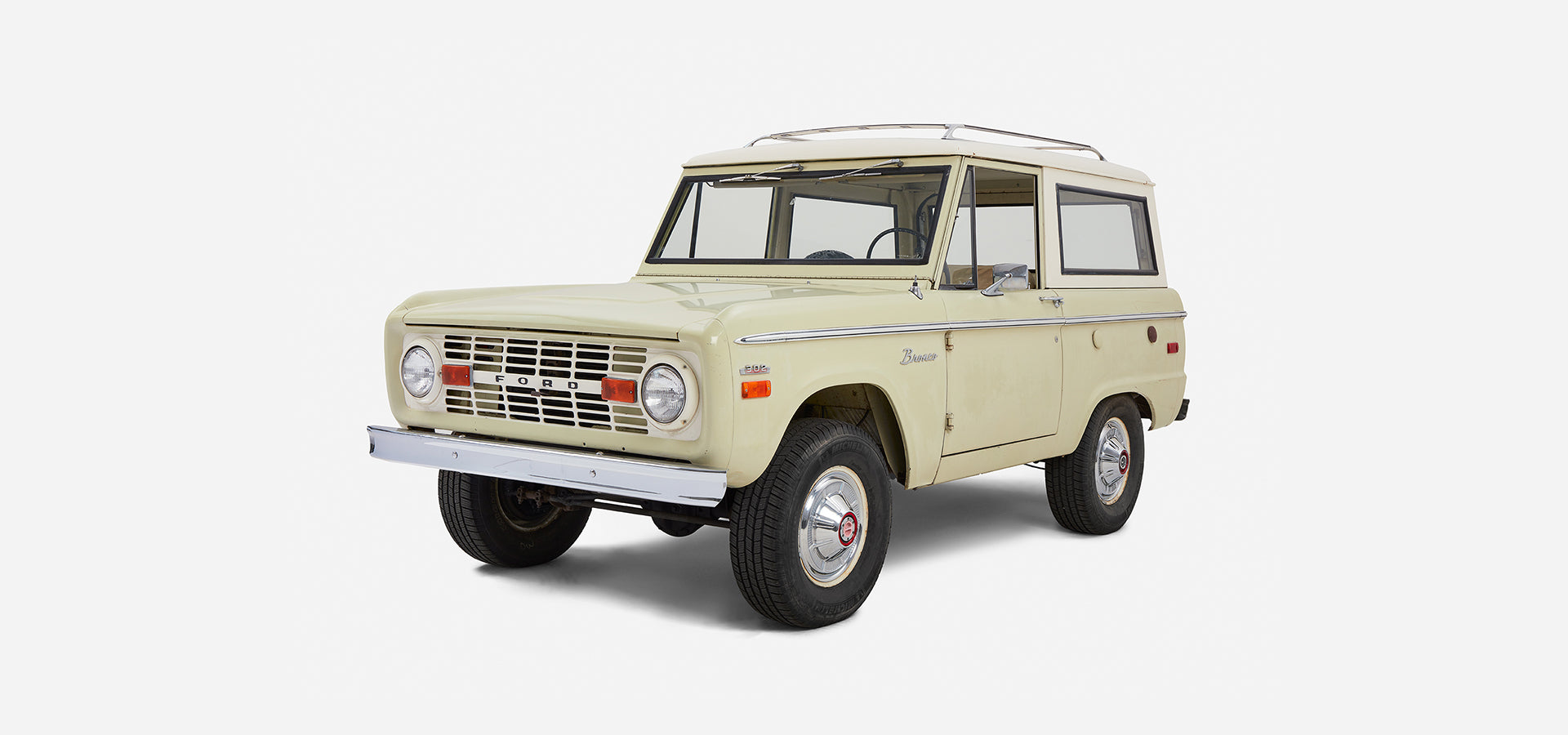 Front three-quarter view of Classic Ford Bronco with white cab and sage body on plain white background