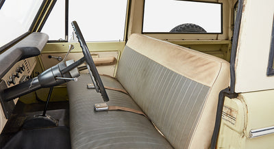 Classic Ford Bronco interior showing front bench seat with patterned fabric and steering wheel