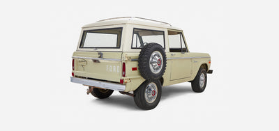 Classic Ford Bronco in light yellow with white roof captured from rear three-quarter view