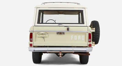 Rear view of light sage green Classic Ford Bronco with white roof and spare tire mounted on back