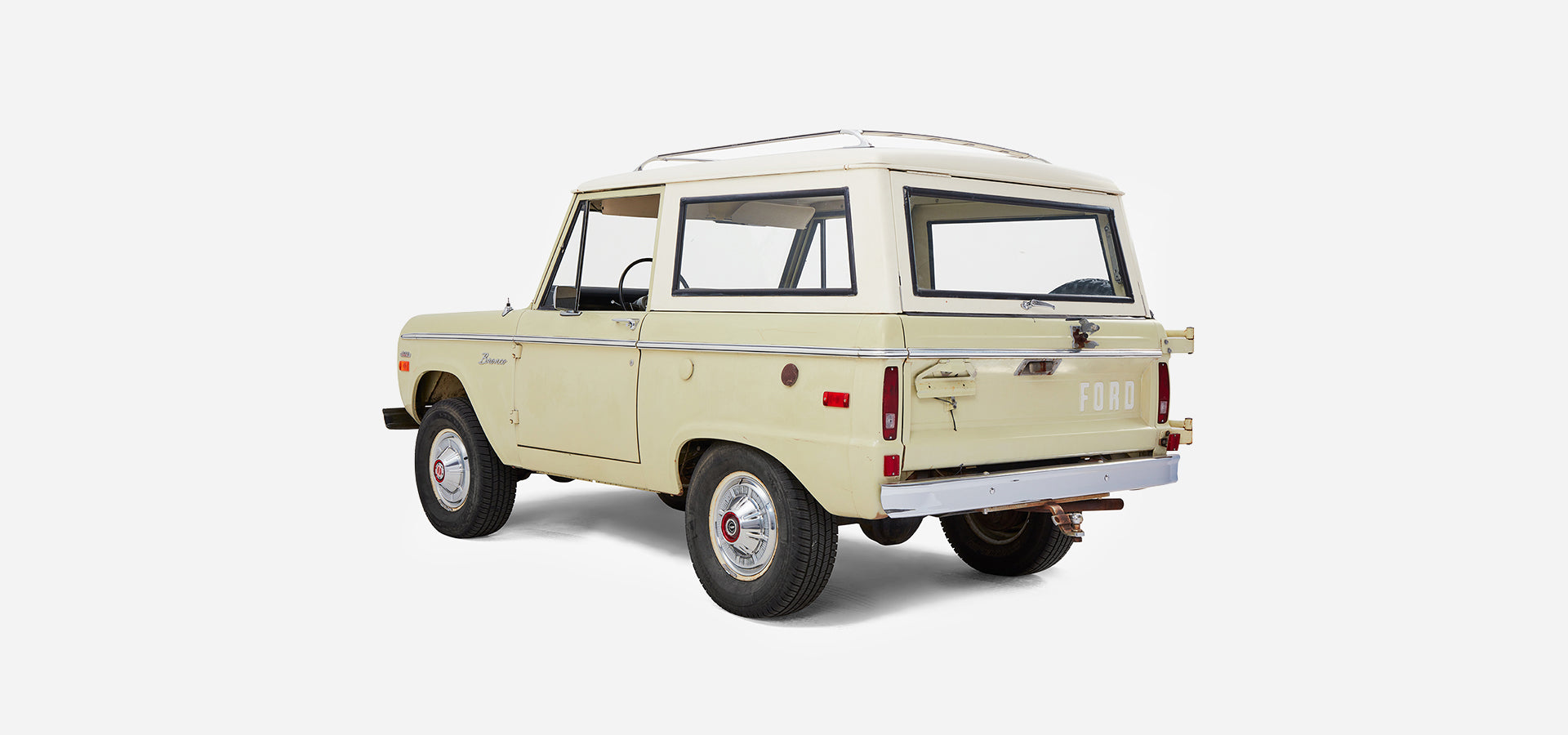 Rear three-quarter view of Classic Ford Bronco with white cab and sage body on white background